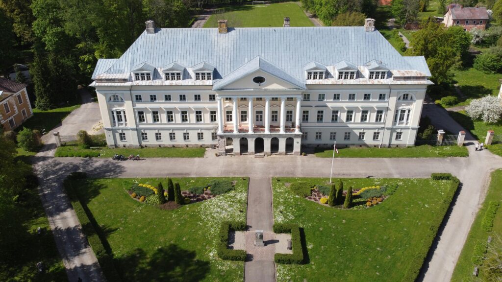 A stunning drone shot of Kazdanga Castle, showcasing its grand architecture and surrounding gardens.