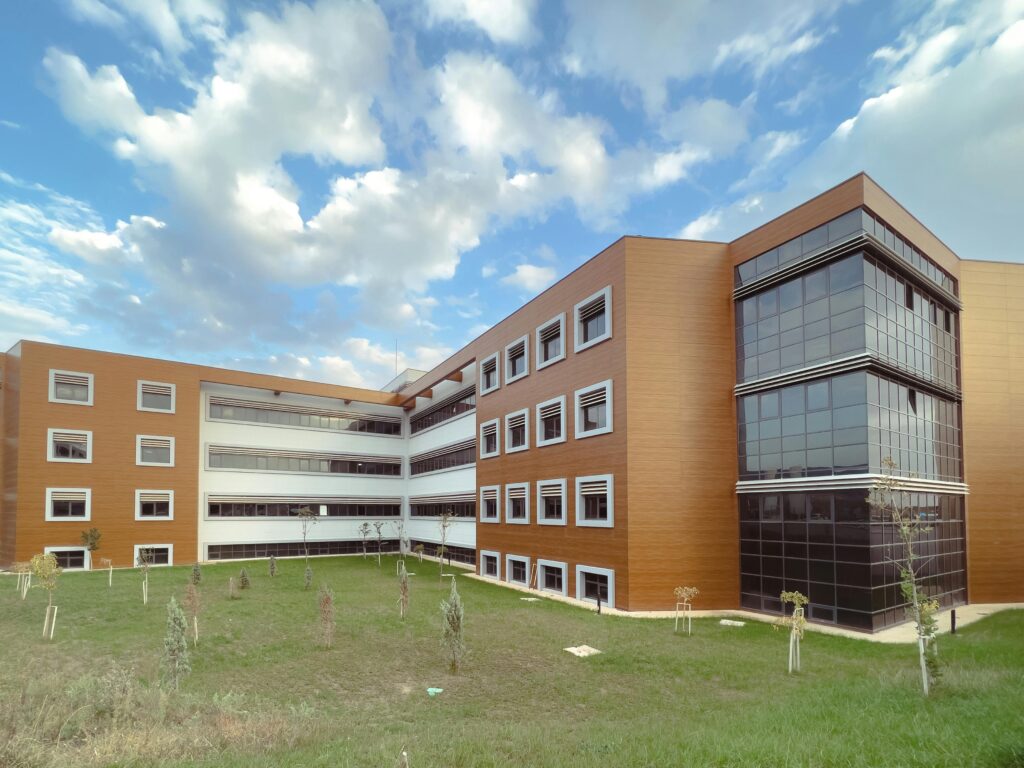 A modern educational building with a grassy lawn and partly cloudy sky.