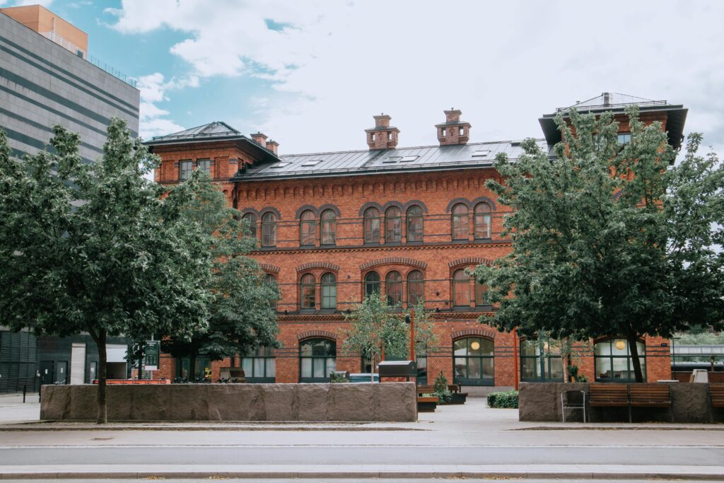 A charming red brick building surrounded by trees in an urban setting on a clear day.